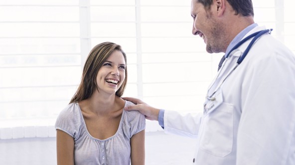 Junge Frau blick lachend zu einem Arzt