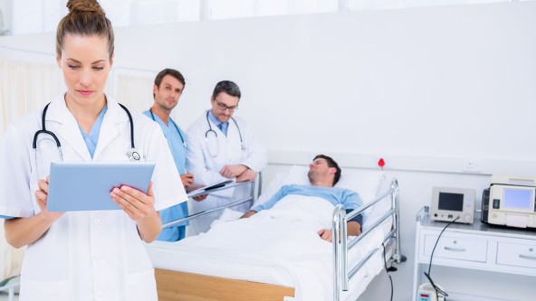 Pflegepersonal im Krankenhauszimmer steht vor einem Bett