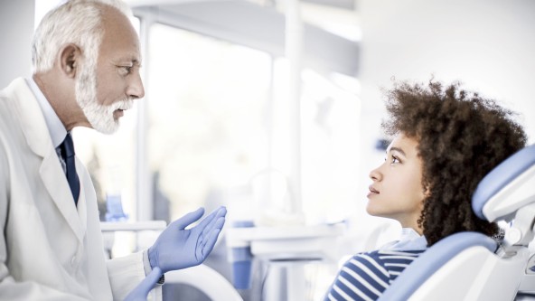 Älterer Zahnarzt untersucht junge Frau auf Untersuchungsstuhl