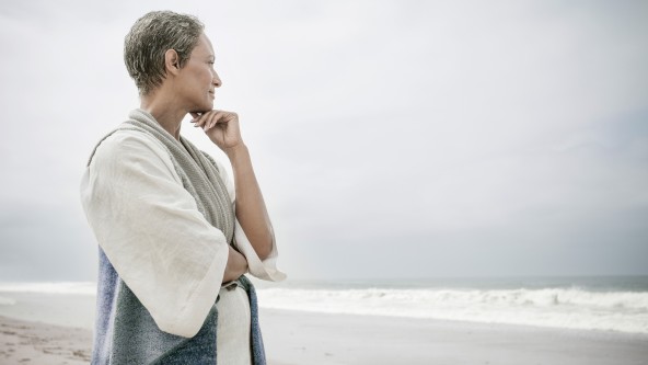 Ältere Frau blickt nachdenklich auf das Meer