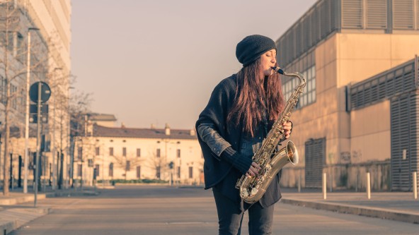 Frau mit Mütze spielt Saxophon auf der Straße
