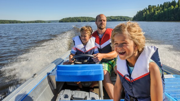 Vater fährt mit 2 Kindern im Motorboot