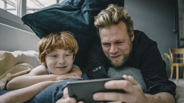Mann zeigt seinem Sohn etwas auf dem Handy
