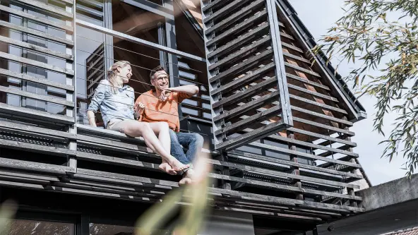 Ehepaar sitzt lachend auf ihrem Balkon
