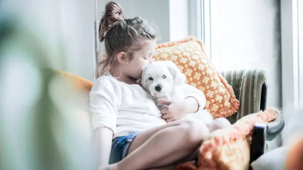 Junge Frau küsst großen Hund an der Wange