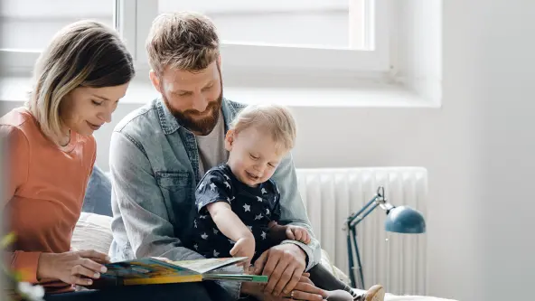 Mutter und Vater blättern mit ihrem Kleinkind in einem Buch