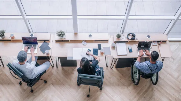 mehrere junge Menschen arbeiten in einem großen Büro an ihren ergonomischen Arbeitsplätzen
