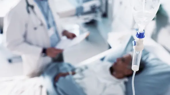 Ein Arzt steht vor dem Krankenbett eines Patienten und stellt eine Diagnose