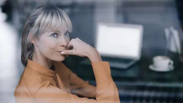 Blonde Frau blickt nachdenklich aus einem Fenster