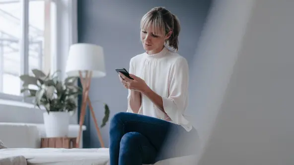 Junge Frau schaut sitzend in ihr Smartphone