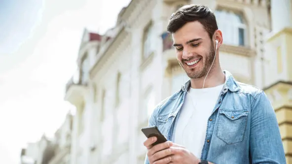 Junger Mann schaut lächelnd auf sein Smartphone