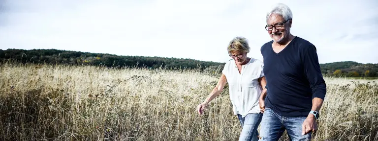 Älteres Paar läuft Hand in Hand über ein Feld