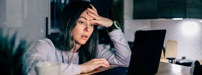 Eine junge Frau sitzt gestresst an einem Laptop im Homeoffice