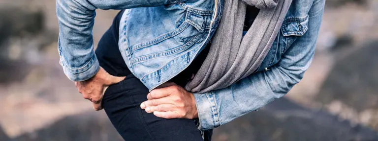 Frau hält sich die schmerzende Hüfte mit beiden Händen