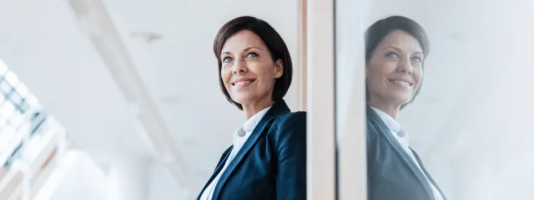 Frau lehnt mit Tablet in der Hand an einer Wand