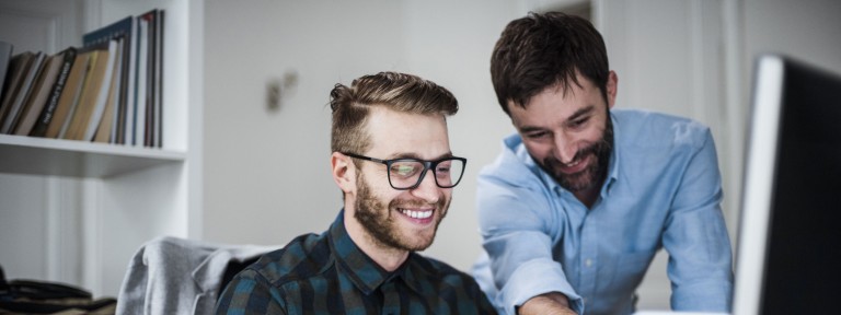 2 junge Männer schauen lachend in einen Laptop