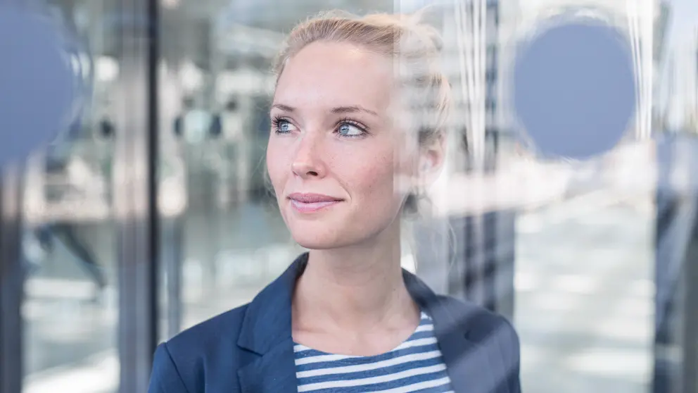 Blonde Frau blickt durch Scheibe in die Ferne