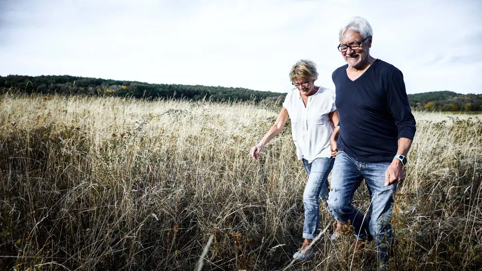 Älteres Paar läuft Hand in Hand über ein Feld