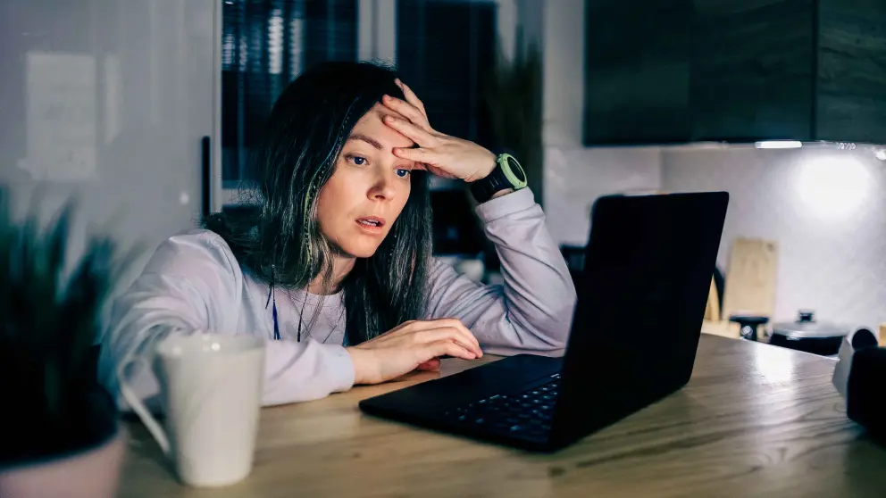 Eine junge Frau sitzt gestresst an einem Laptop im Homeoffice