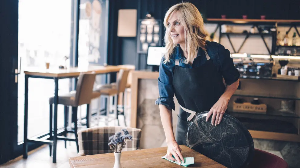 Blonde Frau räumt einen Tisch in einem Restaurant ab