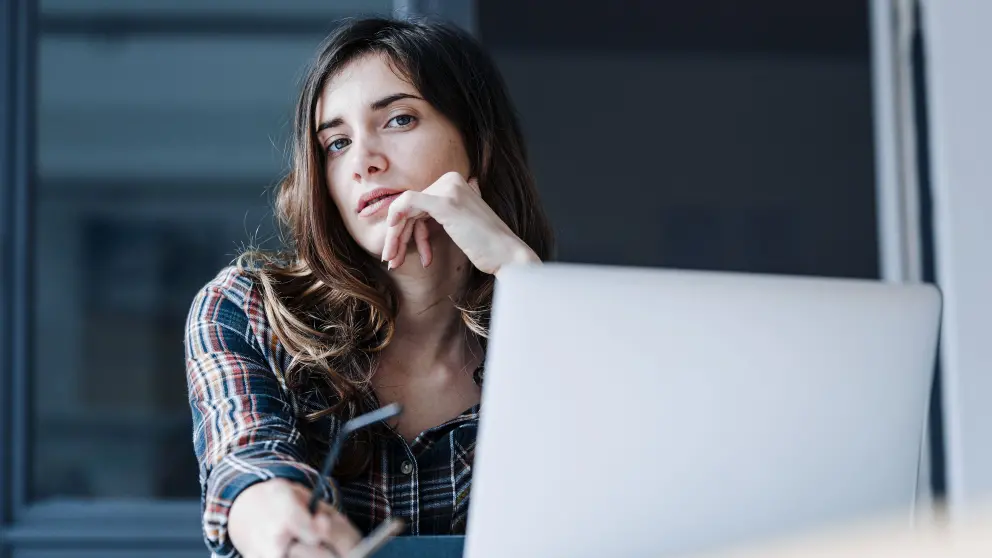 Frau sitz vor Notebook und schaut nachdenklich