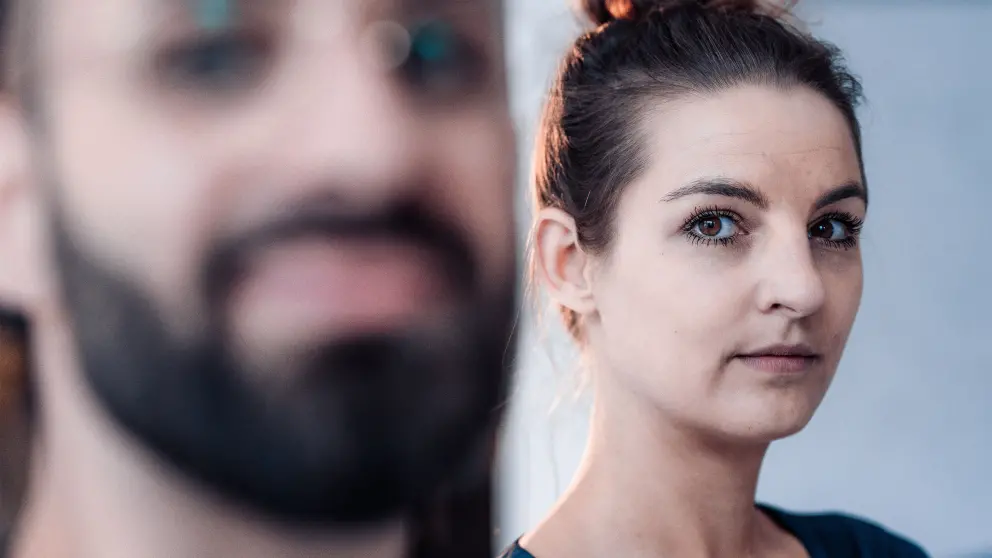 Frau schaut mit strengem Blick hinter einem Mann vorbei