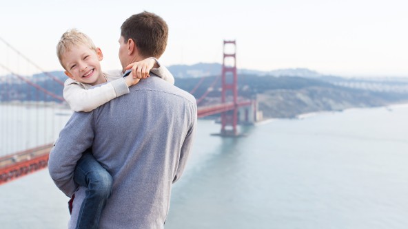 Mann hält Kind am Arm vor der Golden Gate Bridge in San Francisco
