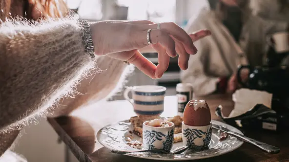 Eine Frau streut Salz auf ein weiches Frühstücksei