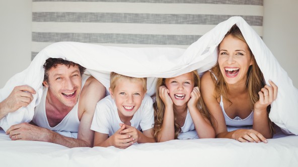 Portrait einer glücklichen Familie unter einer weißen Decke