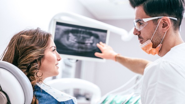 Zahnarzt erklärt einer Frau ein Röntgenbild