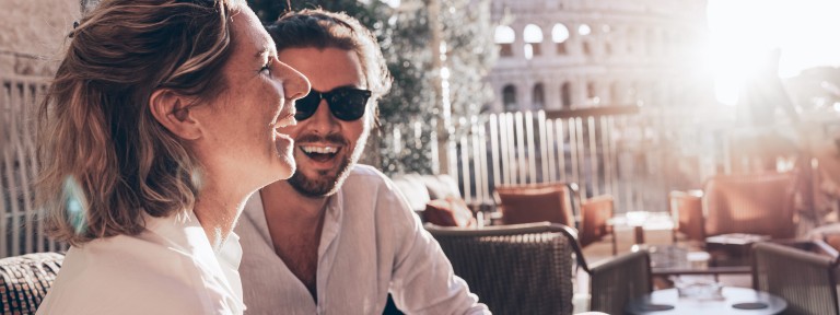 Junges Paar sitzt lachend in einer Bar in Rom