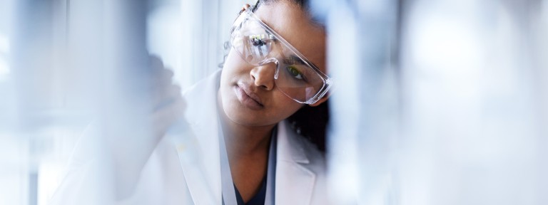 Junge Frau mit Schutzbrille arbeitet in einem Labor