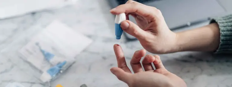 Frau sticht sich in Finger, um zuhause einen Bluttest zu machen