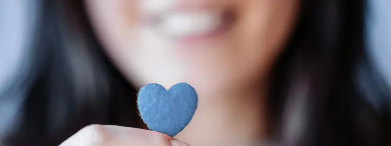 Junge Frau hält ein kleines, graues Herz in der Hand