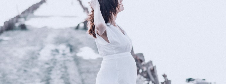 Junge Frau steht im weißen Kleid auf einem Weg