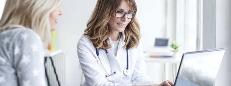 Ärztin mit Brille schreibt etwas an einem Laptop