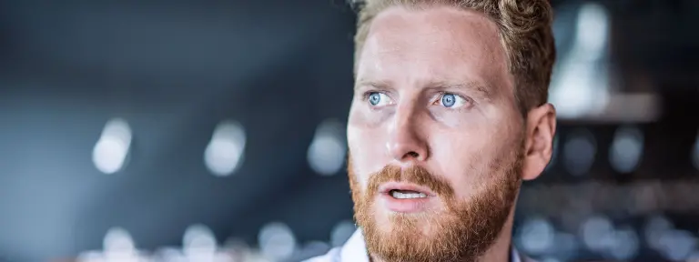 Mann mit Vollbart blickt erschrocken mit großen Augen zur Seite