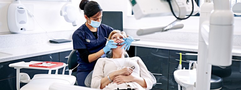 Ältere Frau wird beim Zahnarzt auf Behandlungsstuhl behandelt