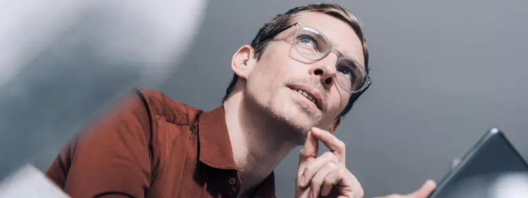 Mann mit Brille schaut nachdenklich zur Seite