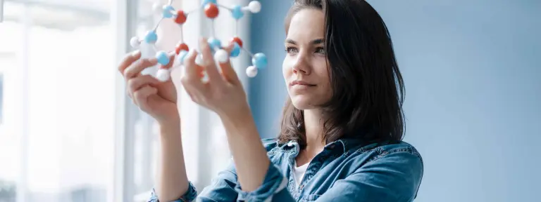 Eine junge Frau schaut sich ein Molekülmodel an