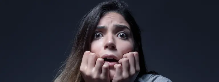 Junge Frau blickt mit erschrockenem Blick in die Kamera