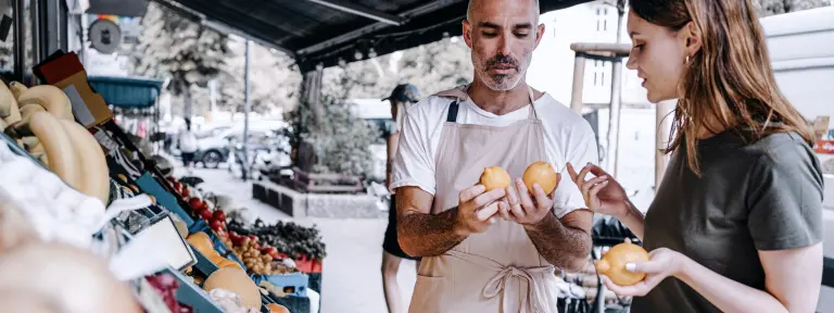 Mann zeigt Frau frische Früchte auf einem Markt
