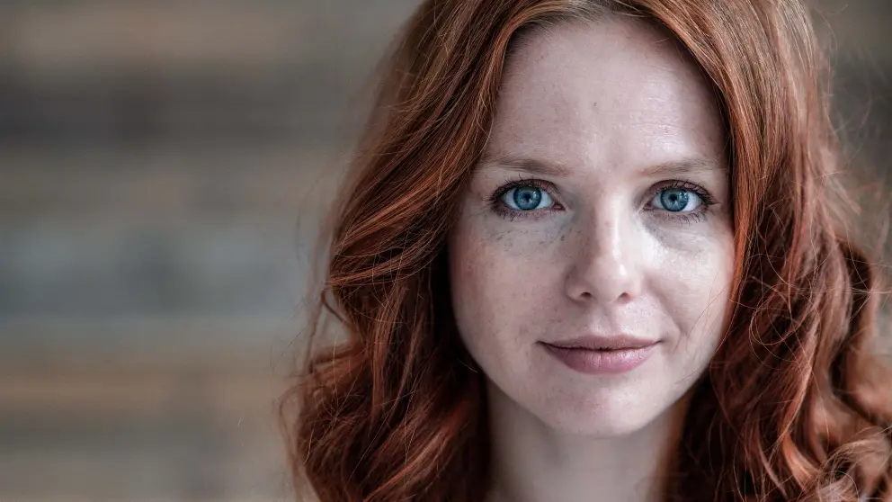 Junge rothaarige Frau schaut mit ihren blauen Augen direkt in die Kamera