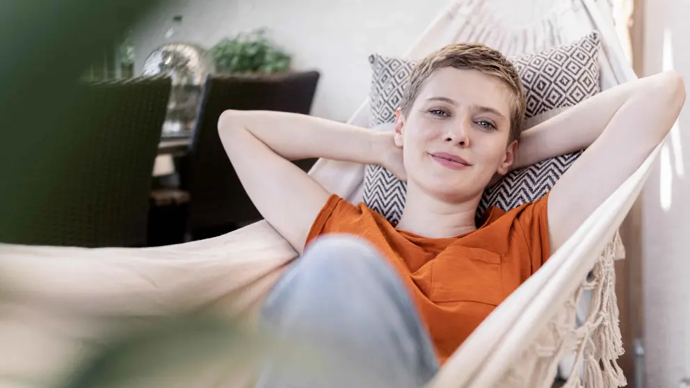 Junge Frau mit kurzen Haaren liegt entspannt in einer Hängematte