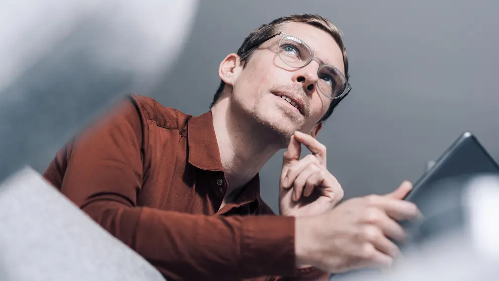 Mann mit Brille schaut nachdenklich zur Seite