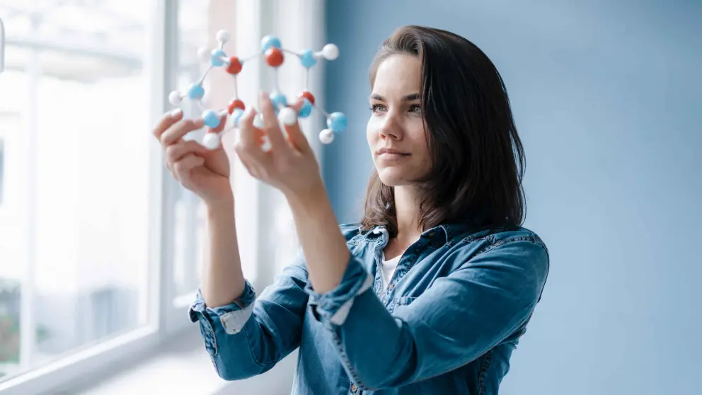 Eine junge Frau schaut sich ein Molekülmodel an