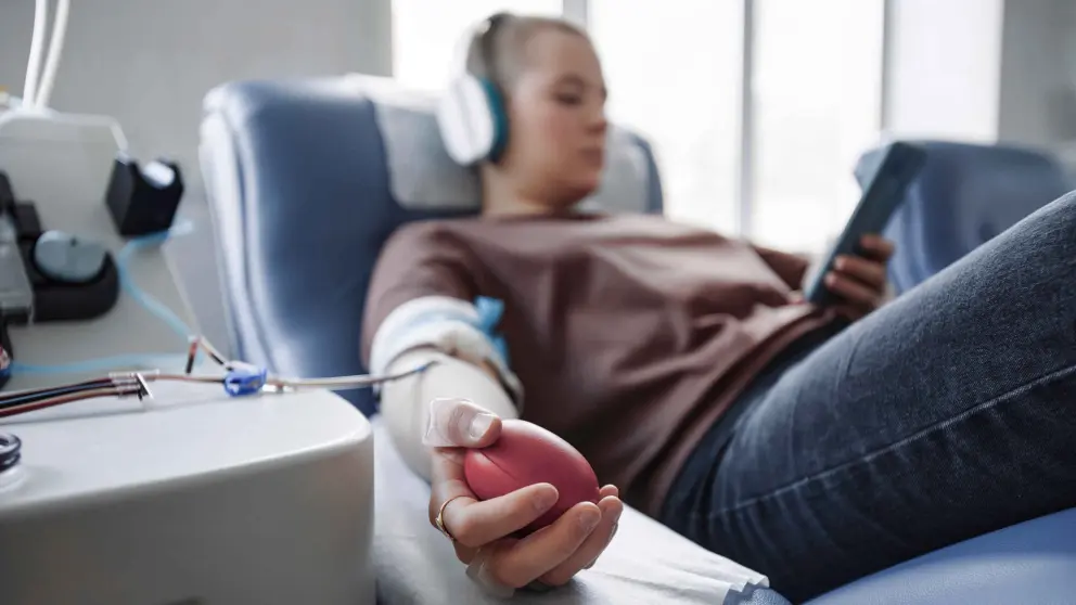 Eine Frau liegt auf einem Krankenbett und ist an ein Dialysegerät angeschlossen