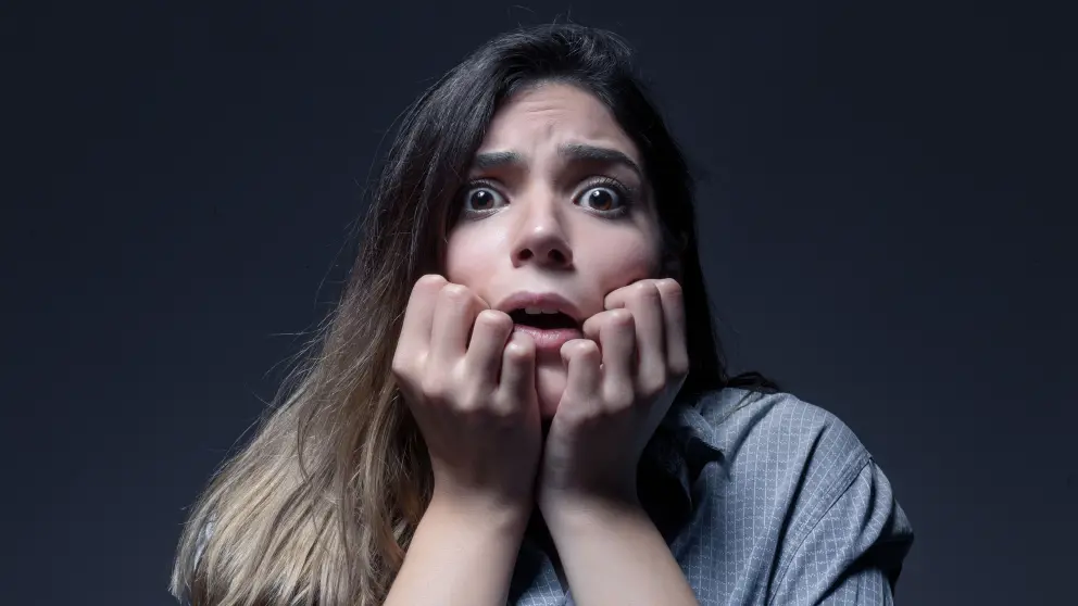 Junge Frau blickt mit erschrockenem Blick in die Kamera