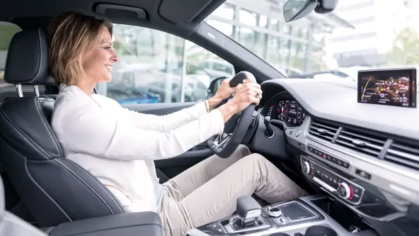Frau sitzt lachend am Steuer eines Autos