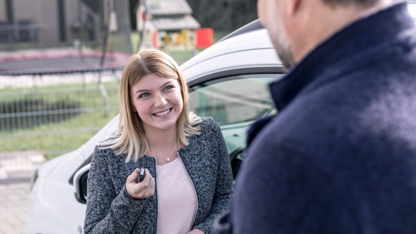 Junge Frau zeigt einem gegenüberstehenden Mann den Autoschlüssel
